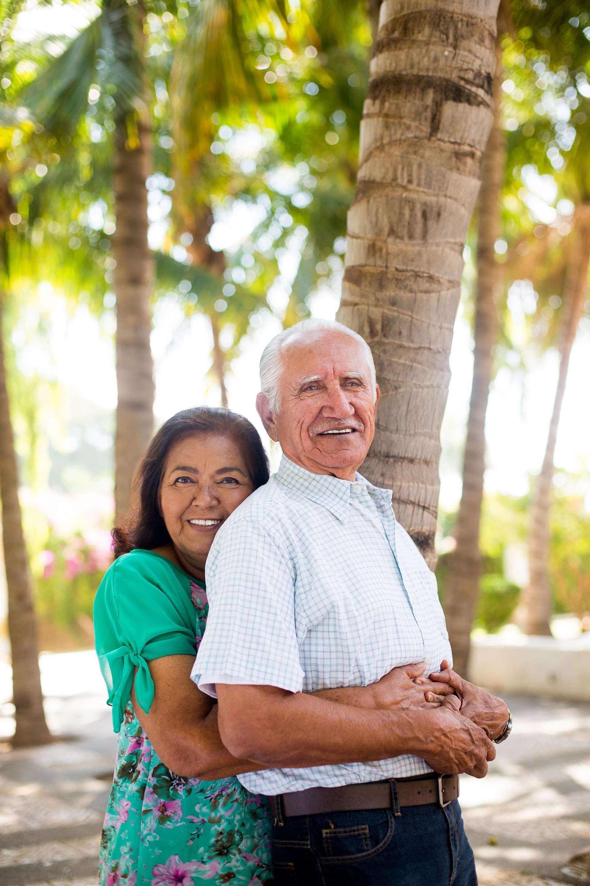Senior pareja sonriendo a acogedor y árboles de palma